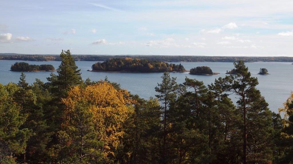 Maisema korkealta mäeltä puiden latvojen yli merelle, jossa näkyy muutama metsäinen saari.